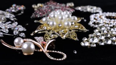 Eski kostüm mücevherleri, kristalli broşlar ve dönen siyah kadife bir vitrin üzerinde yapay inciler..