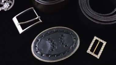 Siyah gerçekten deri kemerler ve farklı dizaynların tokaları siyah kadife arka planda döner.