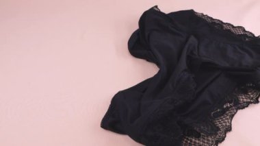 Siyah naylon kadın taytı pembe çarşafın üzerine düşer. Kadın iç çamaşırı teması.