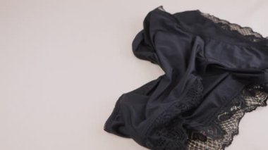 Siyah naylon kadın taytı çarşafa sarılmış iç çamaşırının yanına düşer. Kadın iç çamaşırı teması.