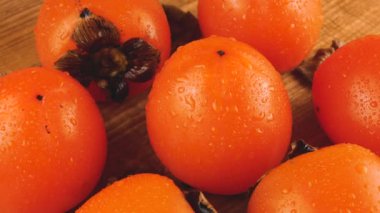 Taze olgun hurma meyveleri ahşap bir tahtanın üzerinde döner. Meyvelerin üzerine bir damla su.