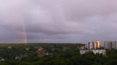 Akşam gökyüzünde büyük bir gökkuşağı Ormanın ve şehrin üzerinde.