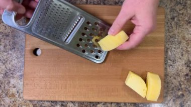 Büyük metal bir rende rendelenmiş peyniri tahta bir tahtaya karşı rendelemek. Üst görünüm.