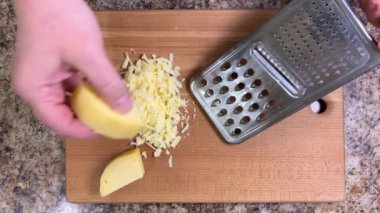 Büyük metal bir rende rendelenmiş peyniri tahta bir tahtaya karşı rendelemek. Üst görünüm.