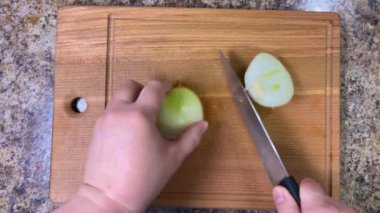 Tahta bir kesme tahtasının üzerinde bıçakla soğanları küçük küplere ayırmak. Üst görünüm.