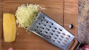 Büyük metal bir rende rendelenmiş peyniri tahta bir tahtaya karşı rendelemek. Üst görünüm.