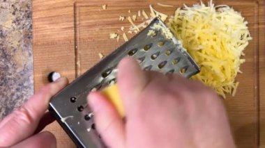 Büyük metal bir rende rendelenmiş peyniri tahta bir tahtaya karşı rendelemek. Üst görünüm.