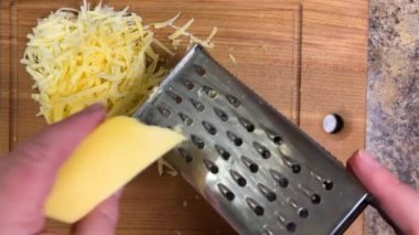 Büyük metal bir rende rendelenmiş peyniri tahta bir tahtaya karşı rendelemek. Üst görünüm.