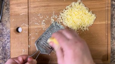 Ahşap bir tahtaya karşı metal rende rendelenmiş peynir. Üst görünüm.