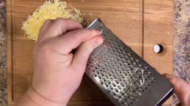 Ahşap bir tahtaya karşı metal rende rendelenmiş peynir. Üst görünüm.