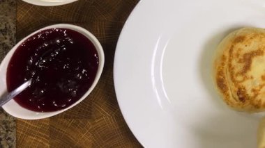 Beyaz tepside smetana ve böğürtlen reçeli ile servis ediliyor. Üst görünüm.