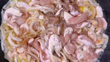 Çiğ tavuk eti, soğan ve baharat kızartma tavasında. Et pişirme sürecinin başlangıcı. Üst görünüm.