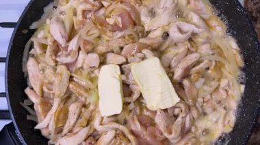 Tereyağı parçaları tavada erimiş tavuk ve soğanla birlikte. Üst görünüm.