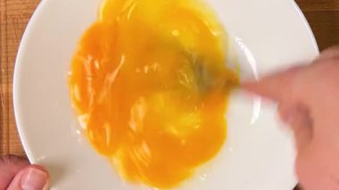 Çiğ tavuk yumurtalarını çatalla tabakta çırpmak. Üst görünüm.