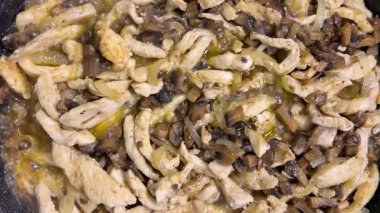 Tavaya tavuk parçaları ve kızarmış mantarla sıcak su ekle. Et pişirme süreci. Üst görünüm.