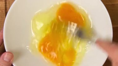 Çiğ tavuk yumurtalarını çatalla tabakta çırpmak. Üst görünüm.