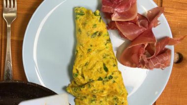 Hazır omlet, jamon dilimlerinin yanına bir tabağa konur. Üst görünüm.