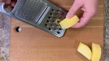 Büyük metal bir rende rendelenmiş peyniri tahta bir tahtaya karşı rendelemek. Üst görünüm.