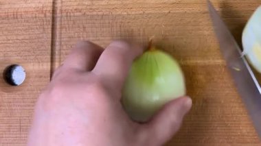 Tahta bir kesme tahtasının üzerinde bıçakla soğanları küçük küplere ayırmak. Üst görünüm.