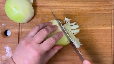 Tahta bir kesme tahtasının üzerinde bıçakla soğanları küçük küplere ayırmak. Üst görünüm.