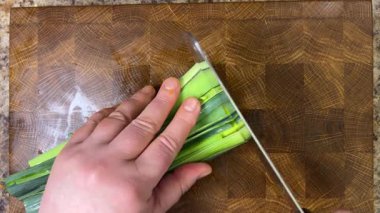 Şef pırasa sapını tahta kesme tahtasında satırla keser..