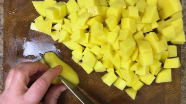 Şef patatesleri tahta kesme tahtasında bıçakla doğruyor..