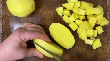 Şef patatesleri tahta kesme tahtasında bıçakla doğruyor..