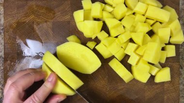 Şef patatesleri tahta kesme tahtasında bıçakla doğruyor..