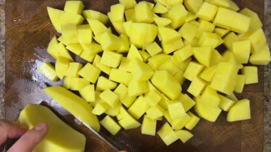 Şef patatesleri tahta kesme tahtasında bıçakla doğruyor..