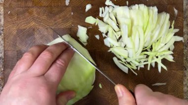 Bir aşçı, ahşap kesme tahtasındaki bıçakla lahana keser..