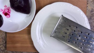 Beyaz tabak arka planında rendelenmiş pancar rendeleniyor.