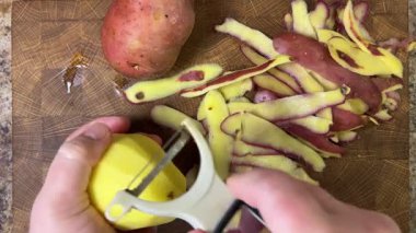 Ahşap kesim tahtasında patates soyan kadın..