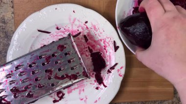 Beyaz tabak arka planında rendelenmiş pancar rendeleniyor.