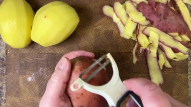 Ahşap kesim tahtasında patates soyan kadın..