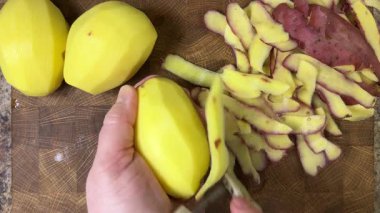 Ahşap kesim tahtasında patates soyan kadın..