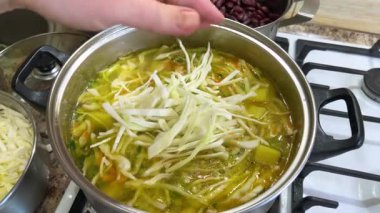 Patates ve havuçla dolu bir tencereye doğranmış lahana ekliyorum. Ukrayna borsası yapma süreci.