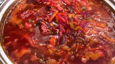 Bir aşçı Ukrayna borşunu kaşıkla tencerede karıştırır. Borş yapma süreci.