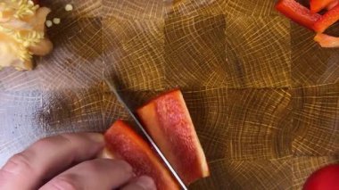 Şef ahşap kesme tahtasındaki bıçakla tatlı biber keser..