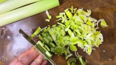 Şef pırasa sapını tahta kesme tahtasında satırla keser..