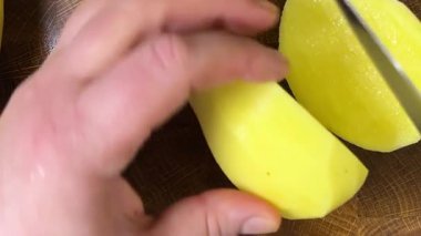 Şef patatesleri tahta kesme tahtasında bıçakla doğruyor..