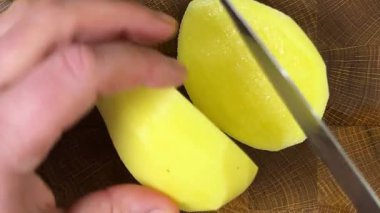 Şef patatesleri tahta kesme tahtasında bıçakla doğruyor..