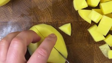 Şef patatesleri tahta kesme tahtasında bıçakla doğruyor..