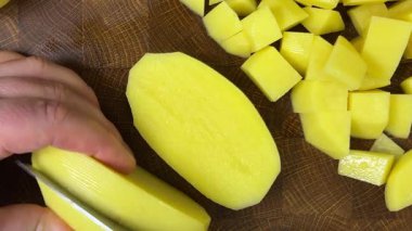 Şef patatesleri tahta kesme tahtasında bıçakla doğruyor..