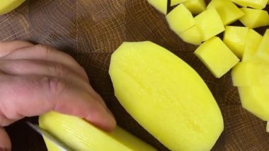 Şef patatesleri tahta kesme tahtasında bıçakla doğruyor..