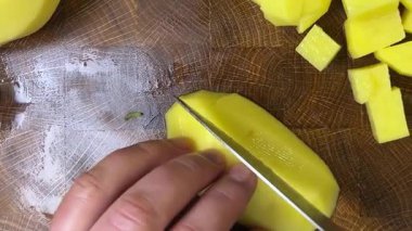 Şef patatesleri tahta kesme tahtasında bıçakla doğruyor..