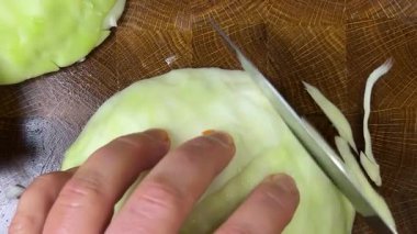 Bir aşçı, ahşap kesme tahtasındaki bıçakla lahana keser..