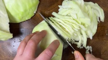 Bir aşçı, ahşap kesme tahtasındaki bıçakla lahana keser..