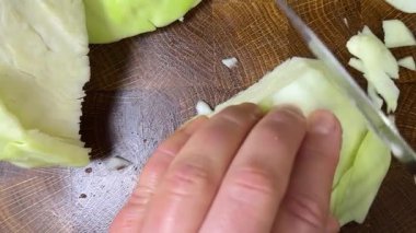 Bir aşçı, ahşap kesme tahtasındaki bıçakla lahana keser..