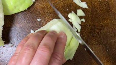 Bir aşçı, ahşap kesme tahtasındaki bıçakla lahana keser..