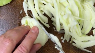 Bir aşçı, ahşap kesme tahtasındaki bıçakla lahana keser..